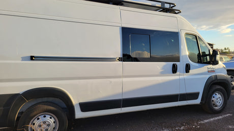 White Ram ProMaster camper van for rv rental, with a side window, roof rack, and awning rail.