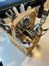 RV rental kitchen: A wicker basket full of shiny utensils (forks, spoons, knives) on a light speckled counter.