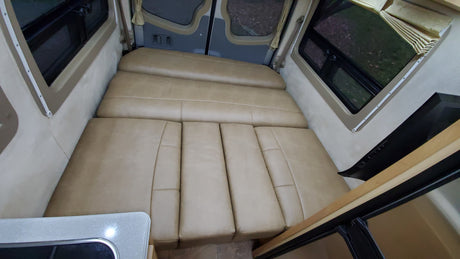 Spacious RV rental interior featuring a comfy convertible bed/seating area and large windows, perfect for travel.