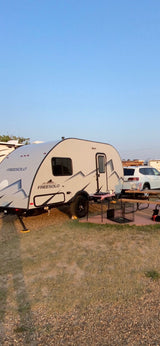 Grey Freesolo RV rental parked at a sunny campsite with outdoor amenities, ready for a cozy camping adventure.