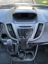 RV rental van's interior: dashboard, radio controls, automatic shifter, cup holders, and phone mount on the center console.
