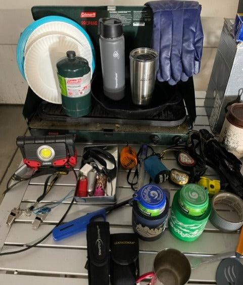 Essential gear for your RV rental: camping stove, propane, plates, water bottles, flashlights, and cooking tools.