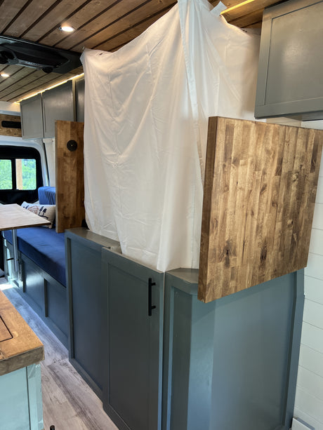 Cozy RV rental interior with compact shower, dining space, and custom cabinetry for mobile adventures.
