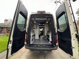 Open rear doors of a clean camper van, perfect for your next RV rental adventure. Spacious interior for travel.