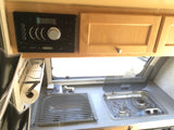 Compact rv rental galley featuring a Jensen stereo, sink, and two-burner stove setup.