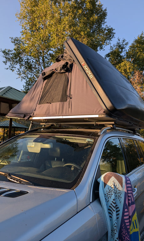Silver SUV with an iKamper rooftop tent set up for camping, a compact RV rental alternative for outdoor adventures.