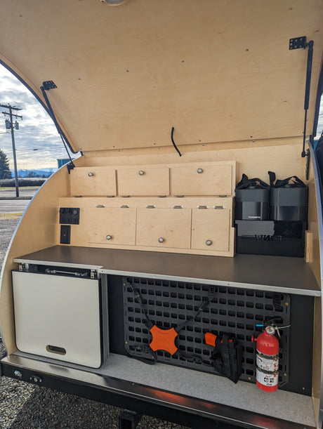 RV rental outdoor galley: organized storage with wooden drawers, power, Dometic gear, and a MOLLE panel with a fire extinguisher.