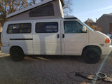 White pop-top camper van, great for your next RV rental adventure, parked on gravel.