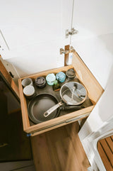 RV rental kitchen drawer showcases organized pan, pot, oil, and travel mugs for efficient space use.