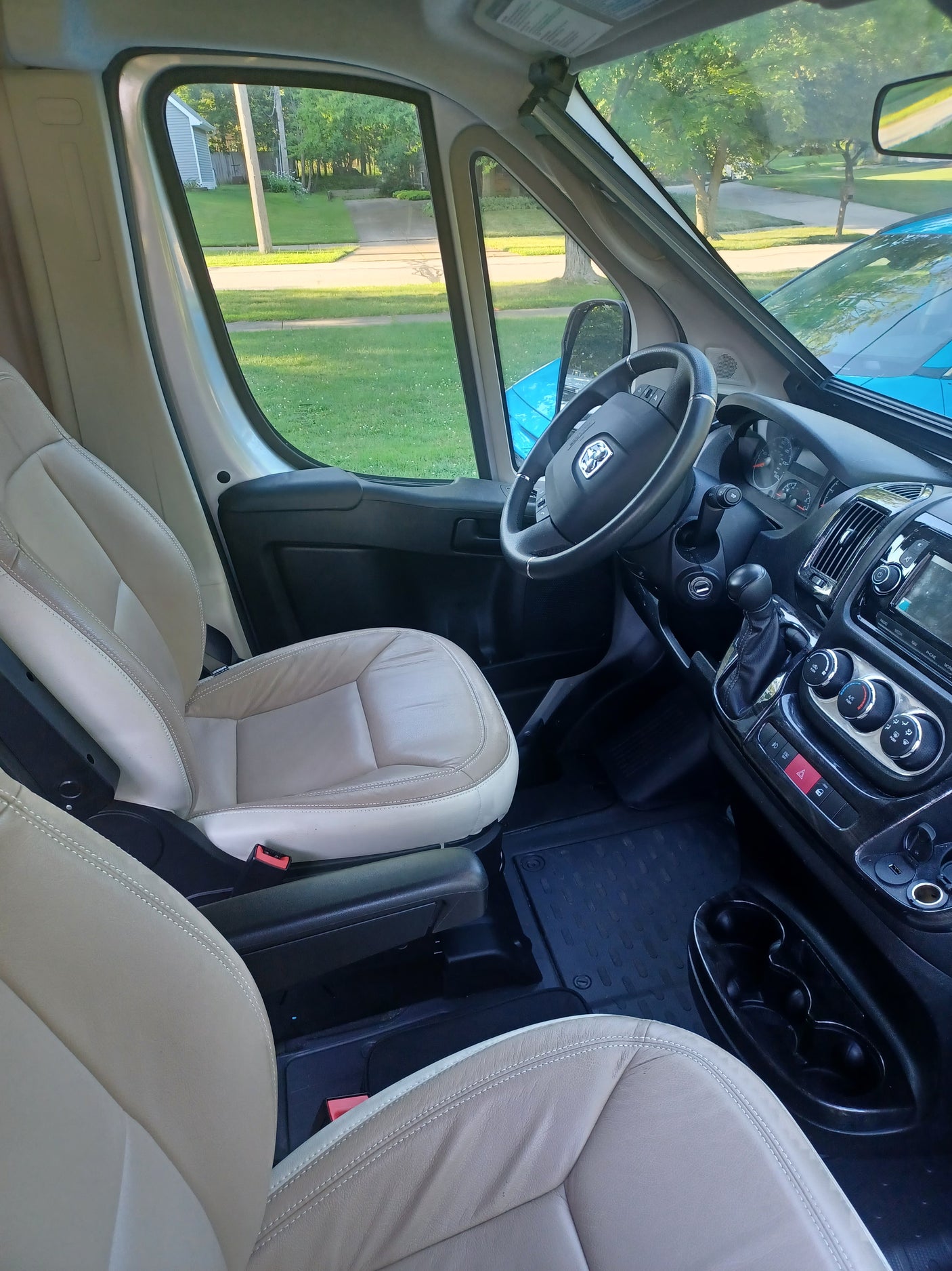 Spacious RV rental interior: Driver's area with steering wheel, dashboard, and comfortable light beige seats.