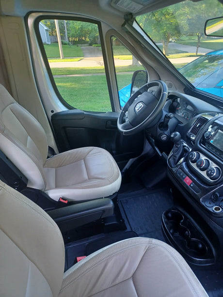 Spacious RV rental interior: Driver's area with steering wheel, dashboard, and comfortable light beige seats.
