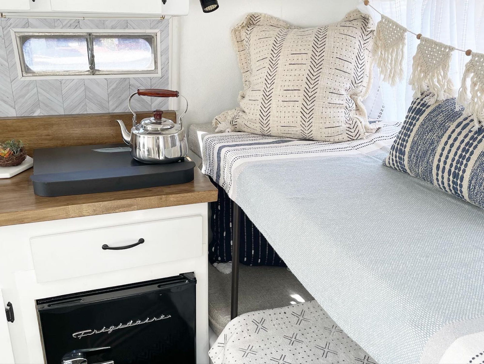 Cozy RV rental interior featuring a compact kitchen with kettle, Frigidaire fridge, and a stylish sleeping nook.