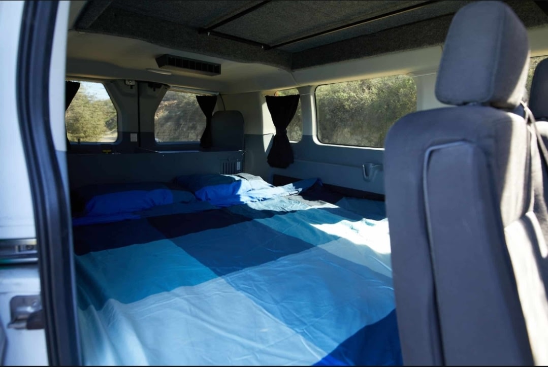  ideal for your next RV rental. Side view of unique custom vehicle.|This rv rental campervan interior features a dining table between two bench seats — photo 7