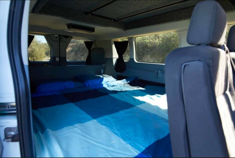  ideal for your next RV rental. Side view of unique custom vehicle.|This rv rental campervan interior features a dining table between two bench seats — photo 7