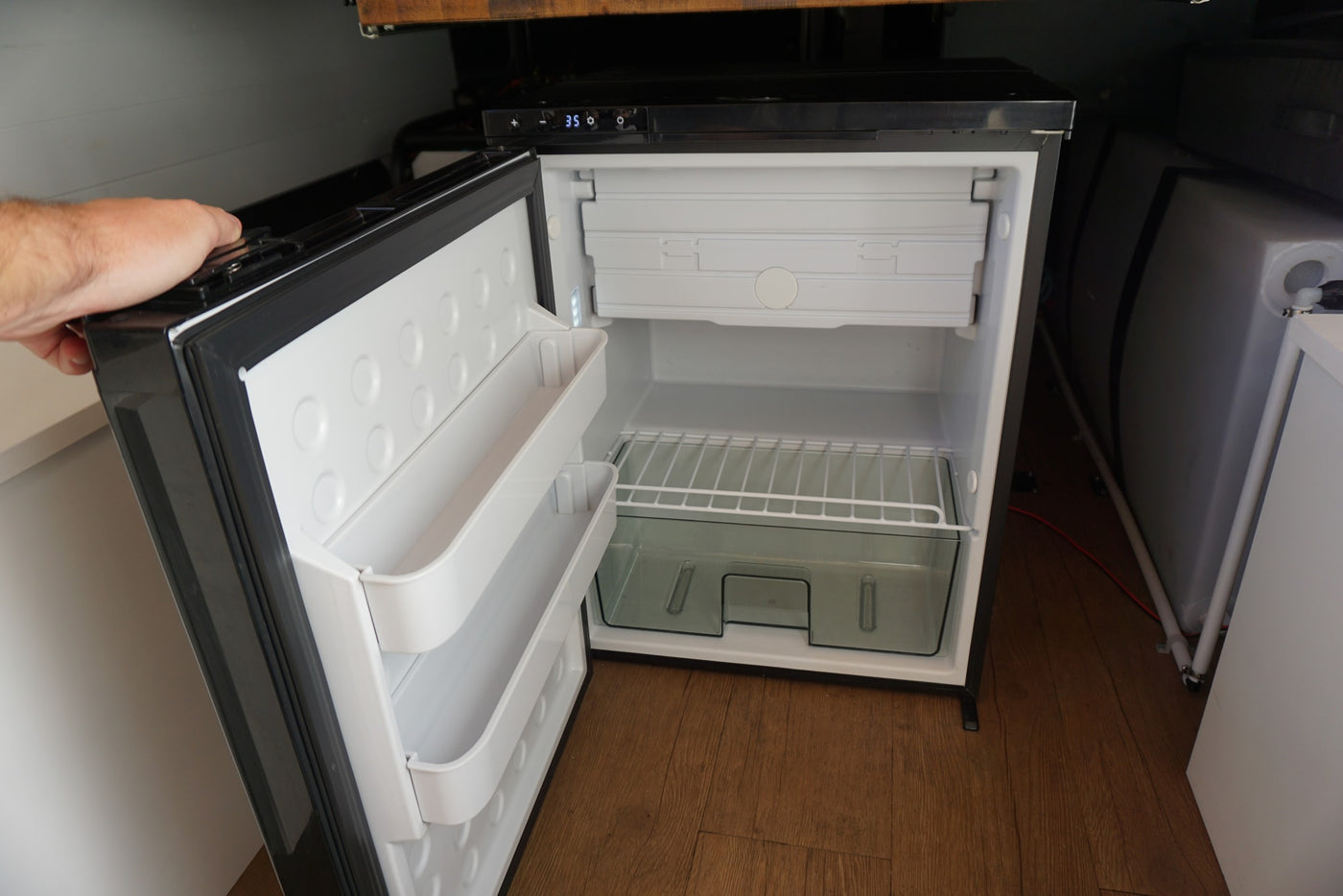  with its side door open showing a modern interior and rooftop AC/solar panels.|Whimsical RV rental ad.|Comprehensive RV rental amenities: full kitchen — photo 11