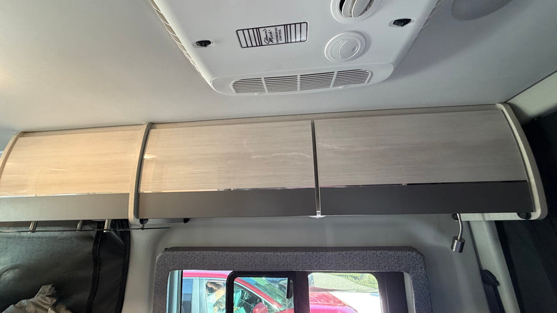  with a lower cabinet. Perfect for storing food and drinks in a camper van.|RV rental's front cabin: A modern Mercedes-Benz Sprinter dashboard with steering wheel — photo 14
