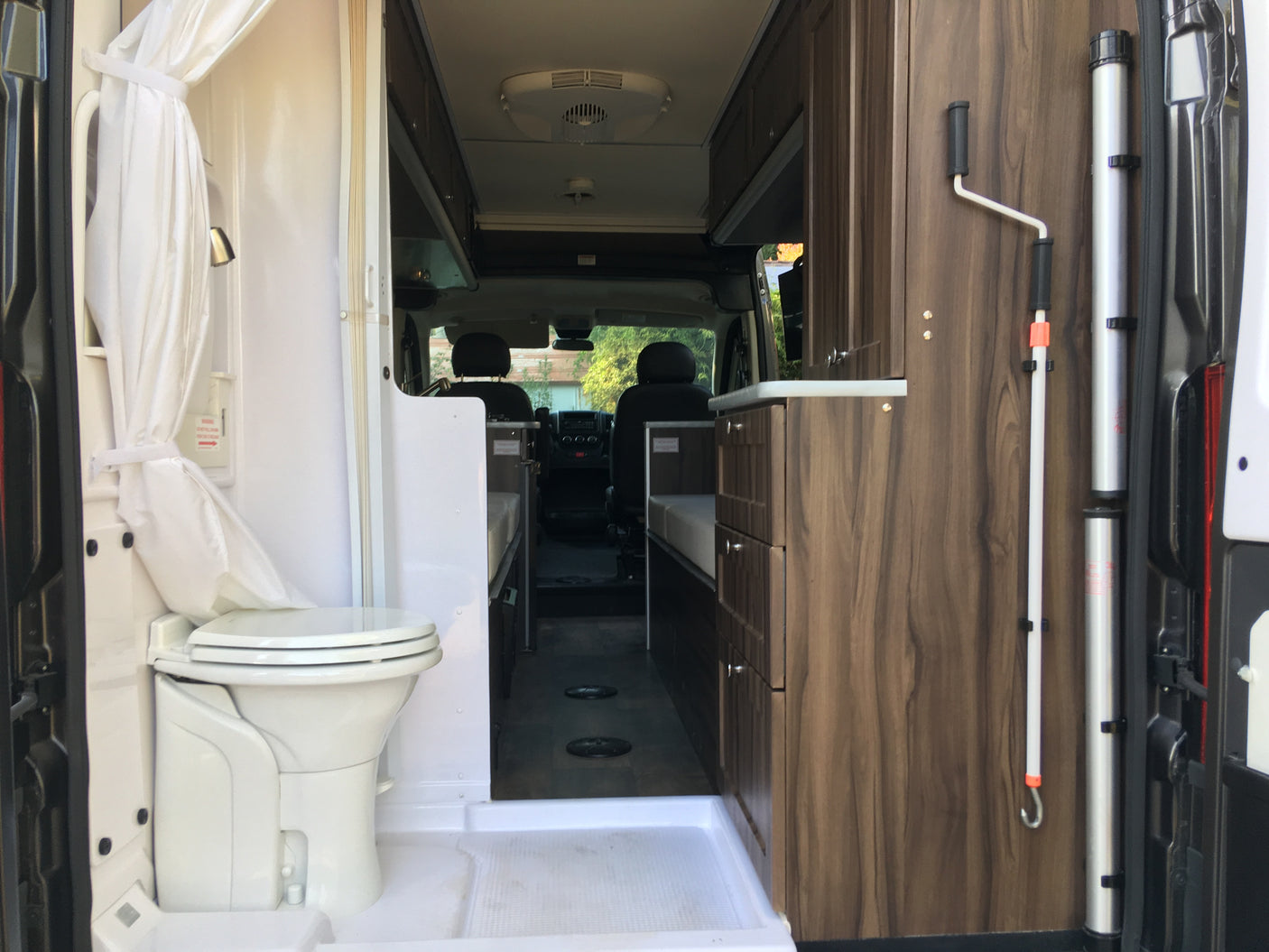 Interior of an RV rental, featuring a compact bathroom with toilet and shower, plus built-in cabinets and living area.