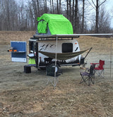 Compact RV rental ready for adventure, with rooftop tent, outdoor kitchen, and chairs for a cozy camp setup.
