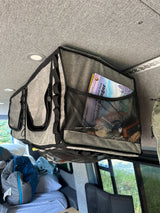 Inside an RV rental: a gray ceiling organizer with mesh pockets holding park guides and keys, optimizing camper van storage for travel.