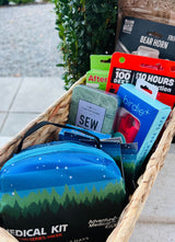Woven basket packed for an RV rental trip: medical kit, bear horn, bug spray, & personal safety items for adventure.