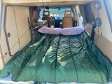 Cozy RV rental interior, showcasing a comfy green sleeping bag and pillows. Perfect camper van setup for a restful trip.