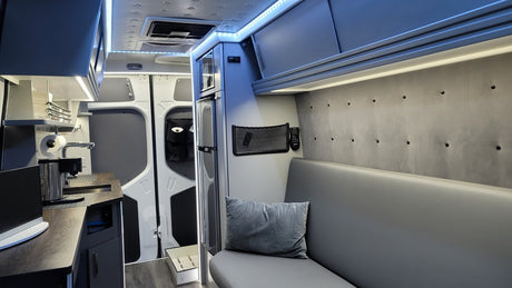 Step inside this sleek RV rental! Enjoy a compact kitchen, fridge, and cozy bench seating with overhead storage for your adventure.