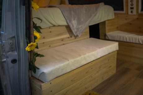 Inside a cozy RV rental: custom wood bunk bed, lower bench, and sunflower garland. A welcoming campervan interior.