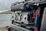 Portable JOOLCA shower & Midnight Forest water tank on an RV rental utility rack. Ideal for overlanding & camping by the ocean.