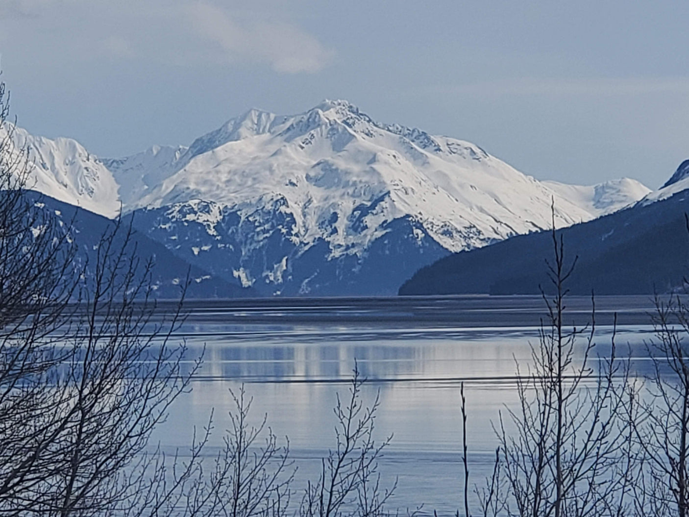 Scenic winter mountain range with reflective water & bare trees. Ideal landscape for an RV rental road trip.