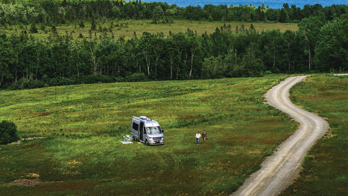  and wall-mounted soap/shampoo dispensers.|An RV rental parked in a scenic grassy field with two people — photo 2