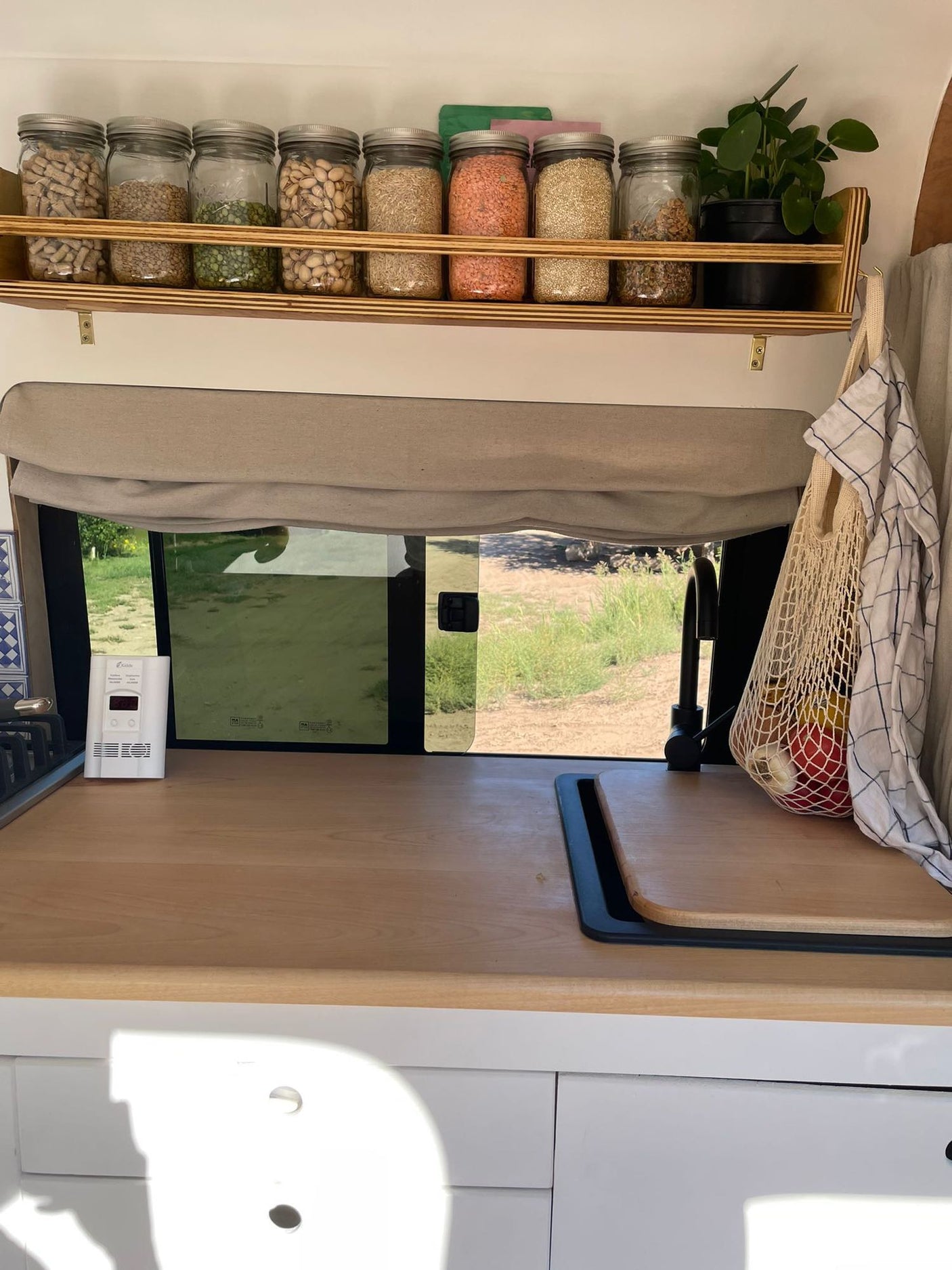 Cozy RV rental kitchen with organized pantry jars, spacious counter, and outdoor view. Ideal for travel.