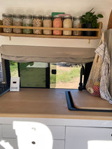 Cozy RV rental kitchen with organized pantry jars, spacious counter, and outdoor view. Ideal for travel.
