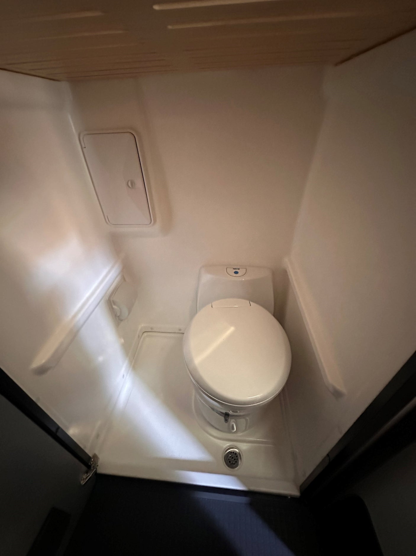 Inside this RV rental, a compact, bright white wet bath features a toilet and an integrated shower drain on the floor.