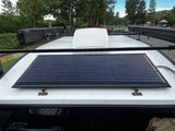 Overhead view of an RV rental roof featuring a large solar panel, roof rack, and side awnings for off-grid adventures.