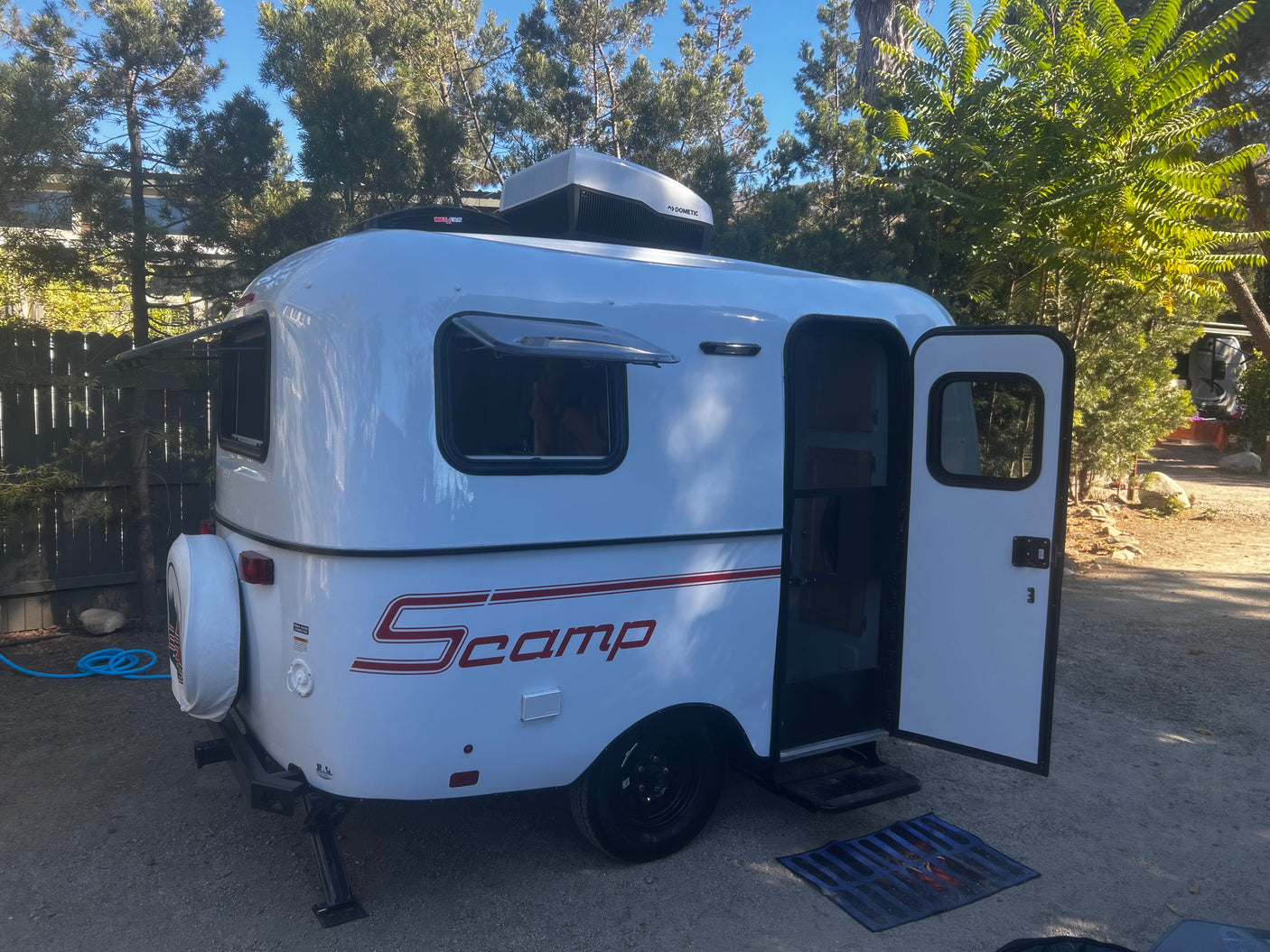 Compact white Scamp travel trailer RV rental, door open & ready for adventure.