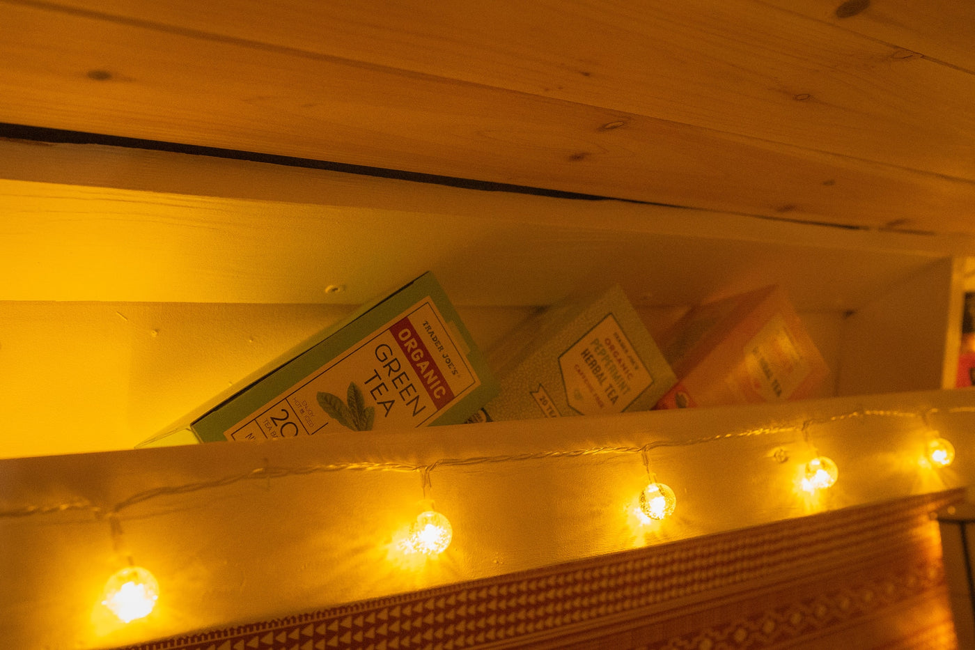 Tea boxes and warm string lights create a cozy ambiance on a shelf inside this inviting rv rental. — photo 10