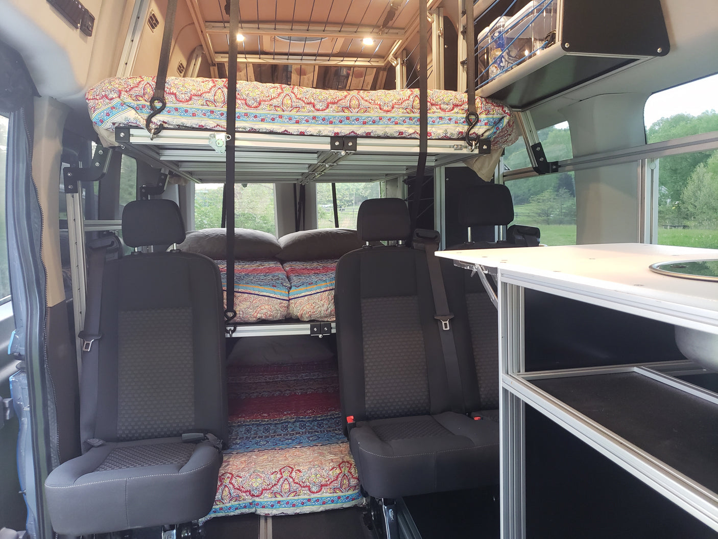 Inside an RV rental: versatile interior featuring modular bunk beds, seating, and a compact kitchen.