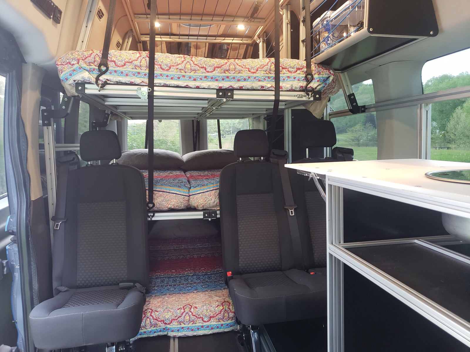 Inside an RV rental: versatile interior featuring modular bunk beds, seating, and a compact kitchen.