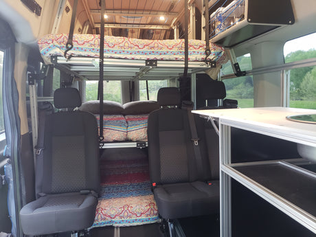 Inside an RV rental: versatile interior featuring modular bunk beds, seating, and a compact kitchen.