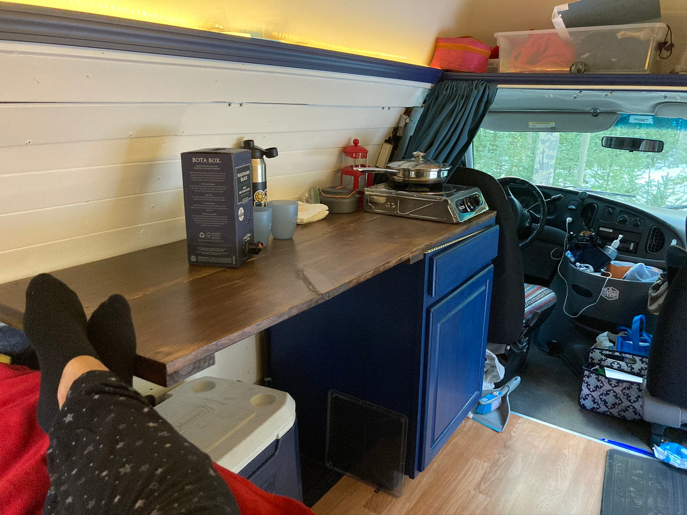 Cozy RV rental interior with a compact kitchen, lounge area, and window views. Perfect for van life.