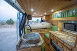 This RV rental's cozy interior boasts a stone sink, full bed, and warm wood finishes, perfect for mobile adventures.