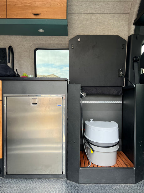 RV rental: Compact camper van interior with fridge, sink, and integrated portable toilet/shower.