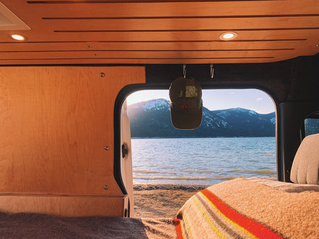 Cozy RV rental interior with stunning lake & snow-capped mountain views. Perfect for your next van life adventure or road trip!