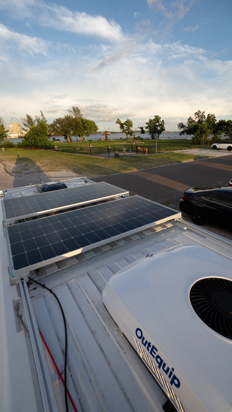 RV rental with rooftop solar panels and OutEquip AC unit, providing a scenic view of a waterfront park. — photo 6