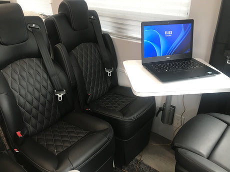 RV rental interior featuring plush seating, laptop on table, and convenient power. Perfect for travel & work.