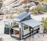 RV rental: Spacious camper van with solar and awning parked in a scenic desert landscape, ready for adventure.