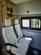 Inside this RV rental: light-colored quilted seats, a control panel for power, and a side window for views.