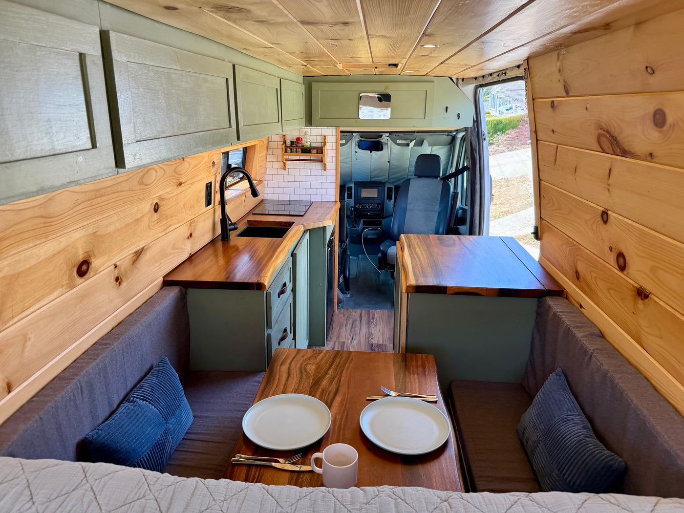 Explore this cozy RV rental camper van! Features a kitchen, dining area, and wood paneling for comfortable adventures. — photo 7