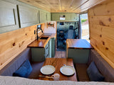 Explore this cozy RV rental camper van! Features a kitchen, dining area, and wood paneling for comfortable adventures.
