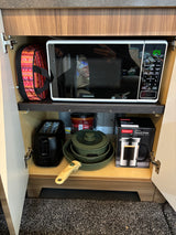 Efficient RV rental kitchen storage: microwave, toaster, cookware, and French press neatly tucked in a cabinet.